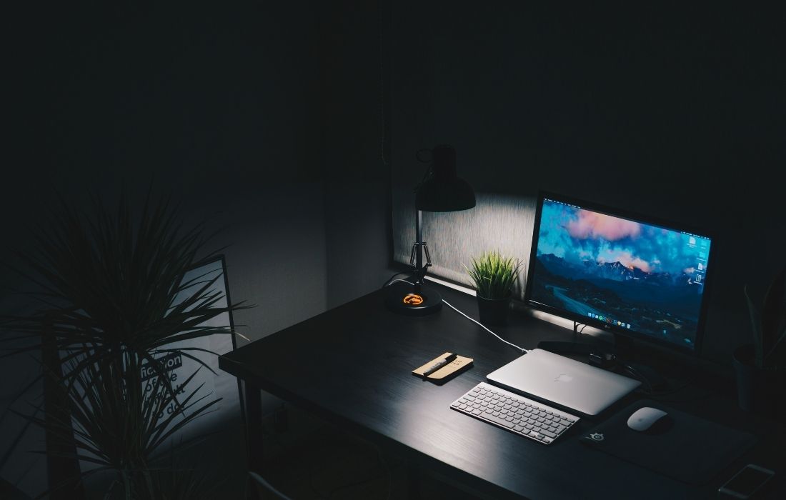 biurko z komputerem w ciemnym pomieszczeniu