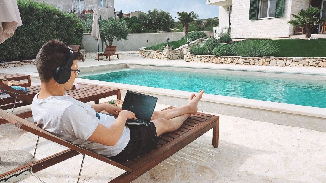 Mężczyzna pracujący na laptopie nad basenem