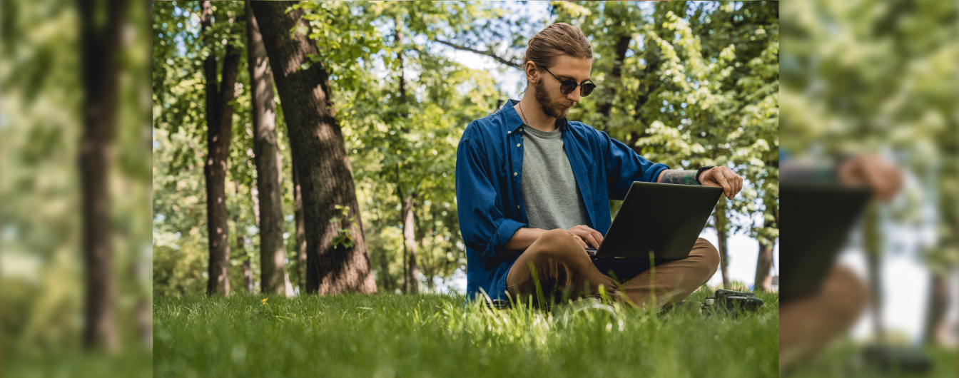 mężczyzna z laptopem siedzi w lesie